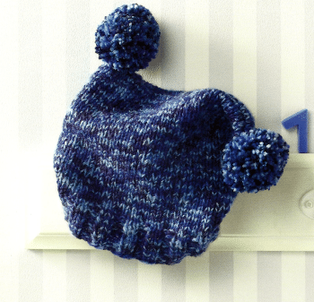 Gestrickter Überzug für eine Babyflasche und Bommelmütze